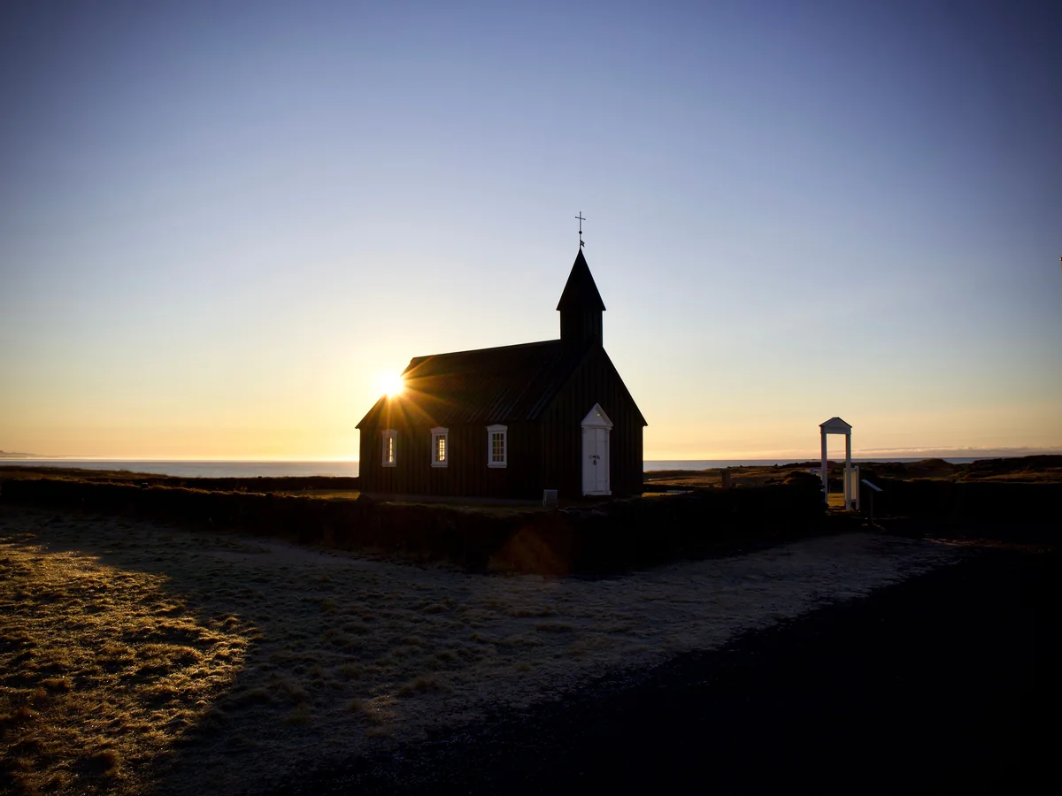 Budakirkja, die kleine schwarze Holzkirche bei Budir, im Sonnenuntergang als Silhouette